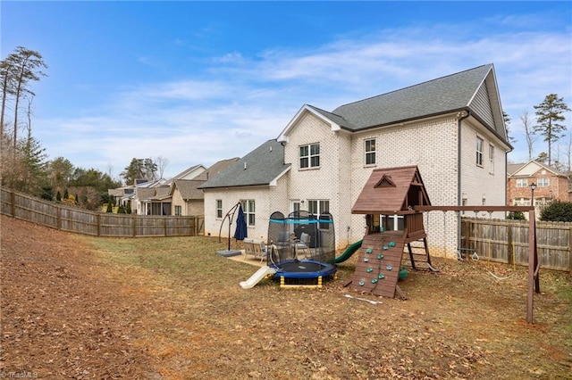 rear view of property featuring a trampoline and a playground