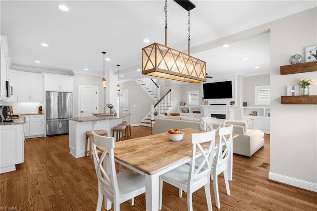 dining space with crown molding, wood-type flooring, and sink