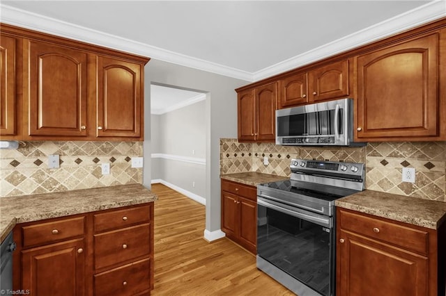 kitchen featuring light wood-style flooring, stainless steel appliances, baseboards, tasteful backsplash, and ornamental molding