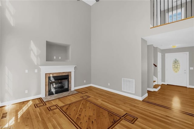 unfurnished living room with stairway, baseboards, wood finished floors, and visible vents
