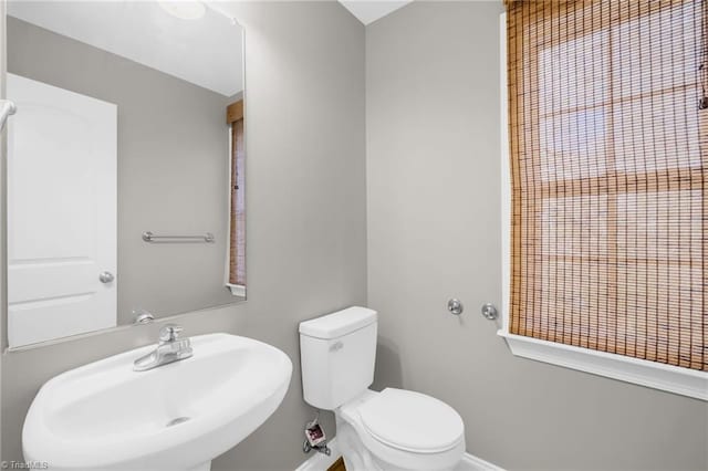 bathroom with baseboards, a sink, and toilet