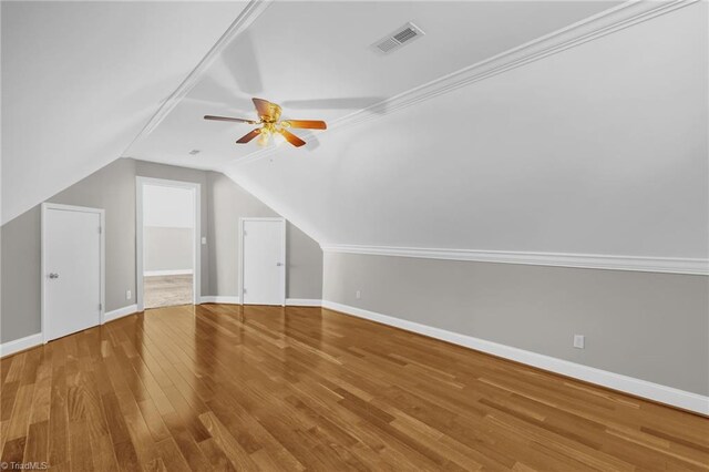 additional living space with visible vents, baseboards, wood finished floors, and vaulted ceiling