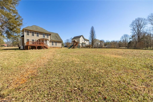 view of yard with a playground, fence, and a wooden deck