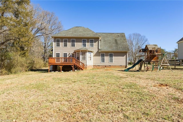 rear view of property featuring crawl space, a lawn, a wooden deck, a playground, and a shingled roof
