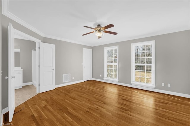 interior space with baseboards, visible vents, ornamental molding, and wood finished floors