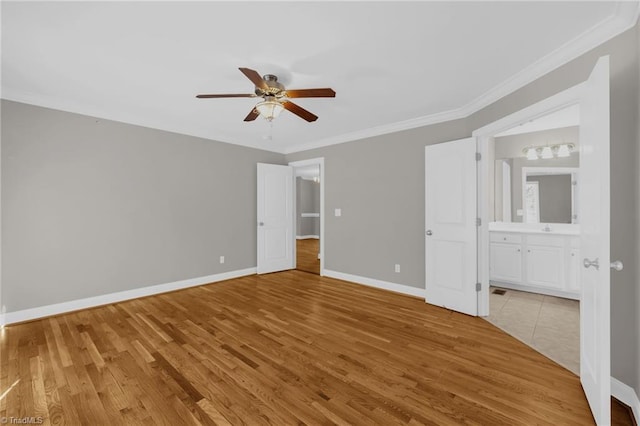 unfurnished bedroom with ceiling fan, ensuite bathroom, baseboards, ornamental molding, and light wood-style flooring