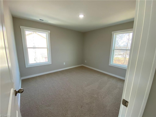 spare room with carpet, visible vents, and baseboards