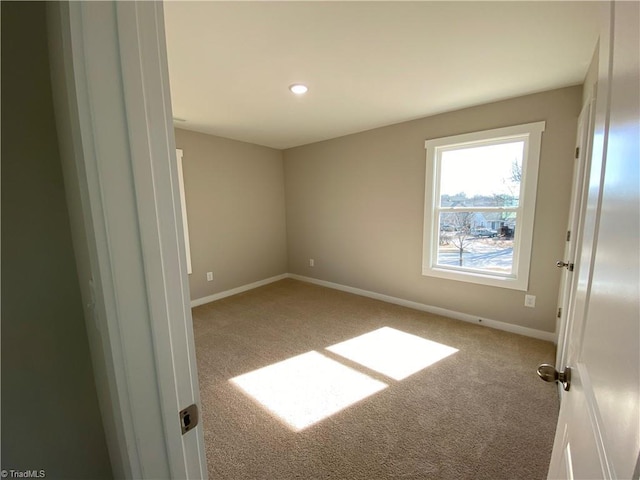 carpeted spare room featuring baseboards