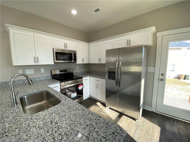 kitchen featuring light stone counters, a sink, white cabinetry, appliances with stainless steel finishes, and dark wood-style floors