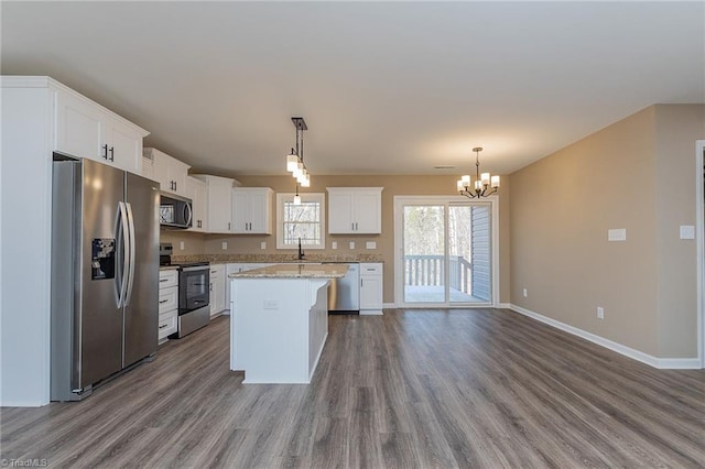 kitchen with appliances with stainless steel finishes, a center island, white cabinets, and decorative light fixtures