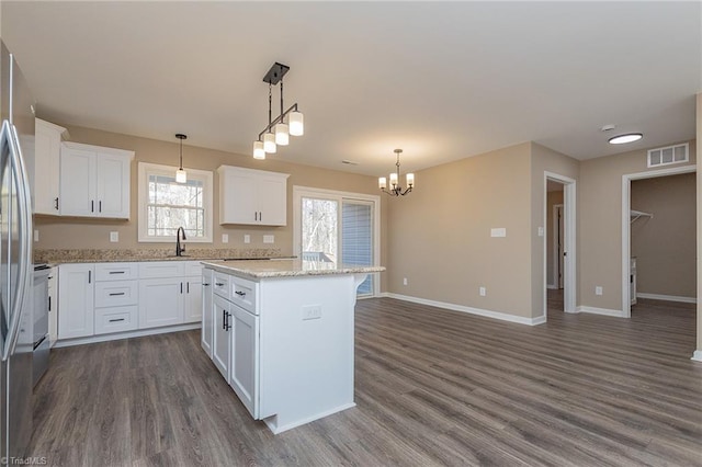 kitchen featuring visible vents, a kitchen island, white cabinetry, and pendant lighting