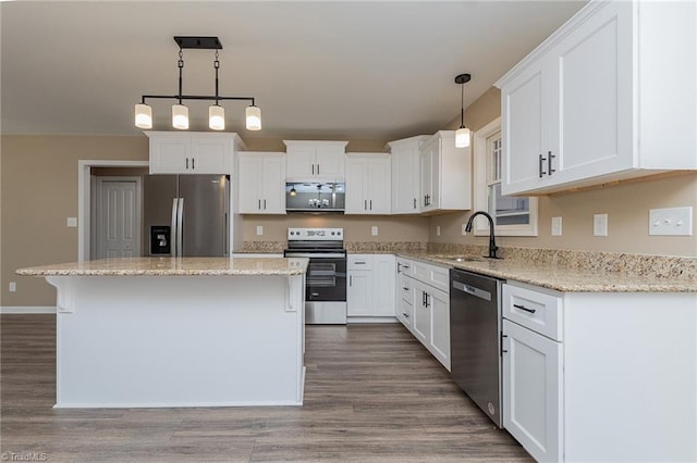 kitchen featuring stainless steel appliances, decorative light fixtures, a sink, and white cabinetry