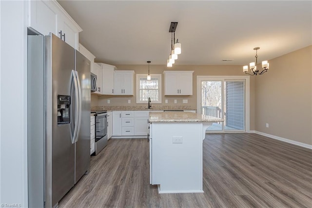 kitchen with a kitchen island, stainless steel appliances, white cabinetry, pendant lighting, and a sink