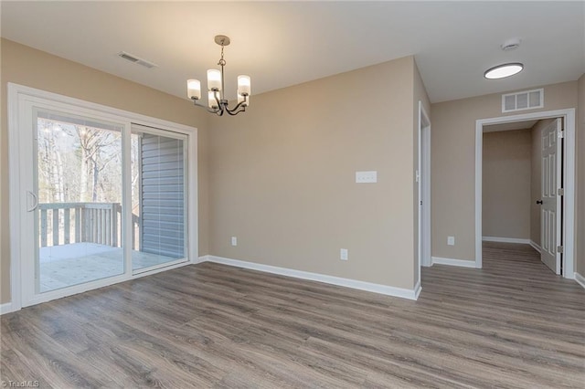 empty room featuring baseboards, visible vents, and wood finished floors