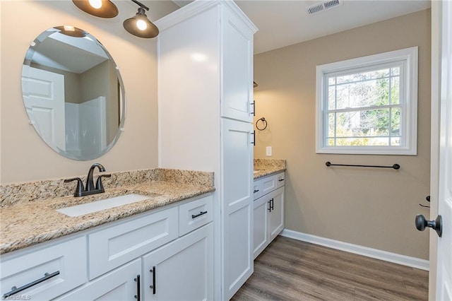 bathroom featuring visible vents, vanity, baseboards, and wood finished floors