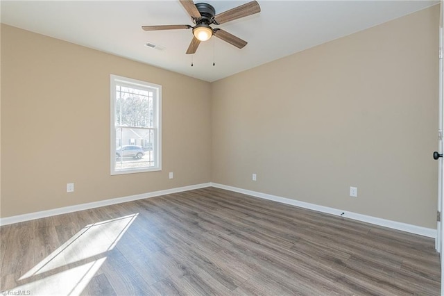 empty room with a ceiling fan, visible vents, baseboards, and wood finished floors