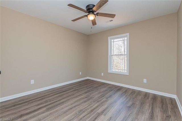 empty room with a ceiling fan, wood finished floors, visible vents, and baseboards