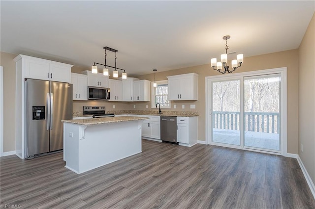 kitchen with stainless steel appliances, hanging light fixtures, white cabinets, and a center island