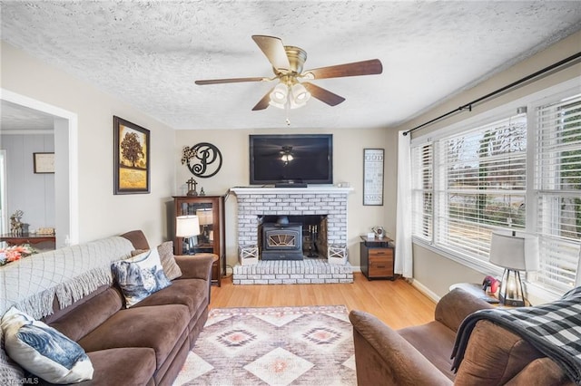 living area with ceiling fan, baseboards, a textured ceiling, and wood finished floors