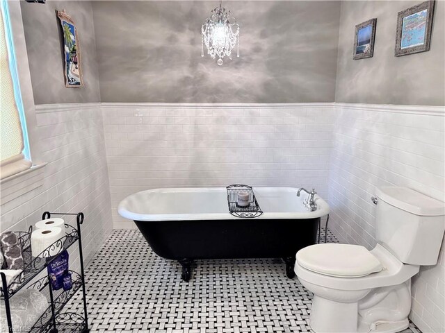 311 Cherry St, Mount Airy, NC 27030 - full bathroom with toilet, tile walls, a wainscoted wall, a soaking tub, and a chandelier