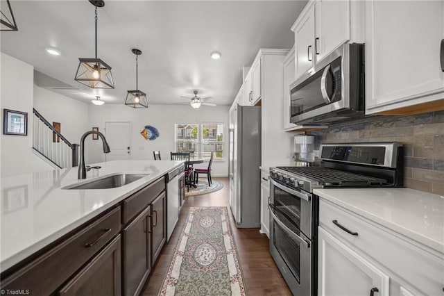 kitchen featuring stainless steel appliances, a sink, light countertops, tasteful backsplash, and dark brown cabinets