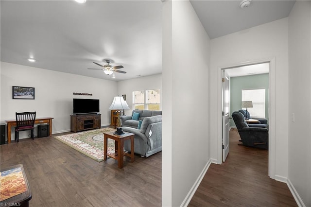 living area with plenty of natural light, ceiling fan, dark wood-style floors, and baseboards