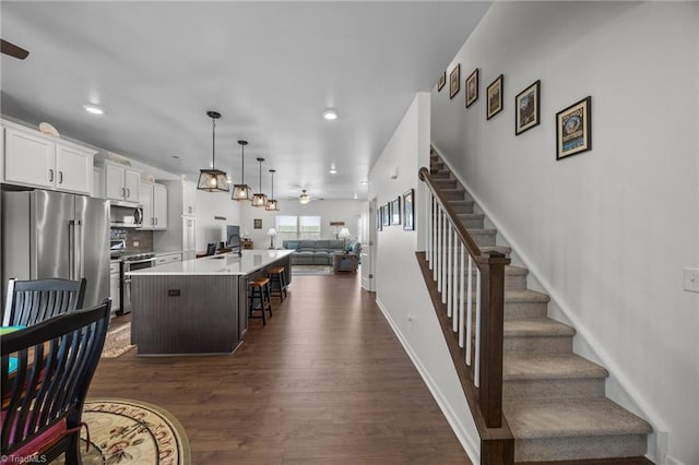 kitchen featuring premium appliances, open floor plan, ceiling fan, a kitchen island with sink, and dark wood-style floors