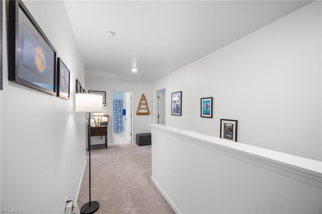 hallway with carpet floors, an upstairs landing, and baseboards
