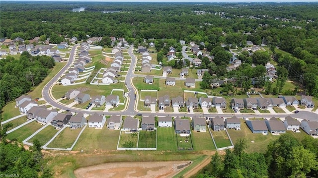 view of property location with nearby suburban area and a heavily wooded area