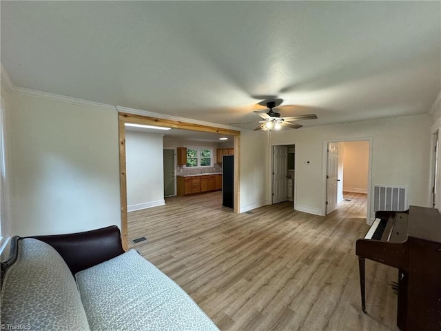 living room with light hardwood / wood-style floors, ornamental molding, and ceiling fan