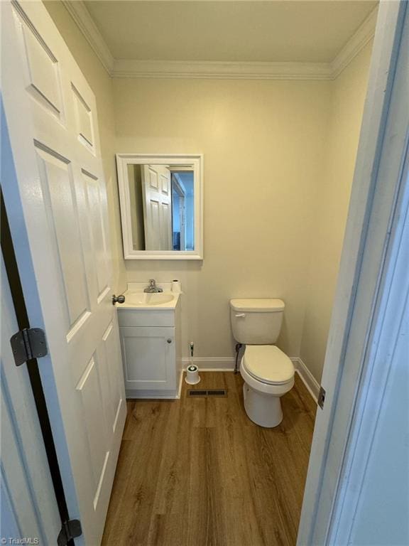 bathroom with hardwood / wood-style floors, vanity, toilet, and ornamental molding