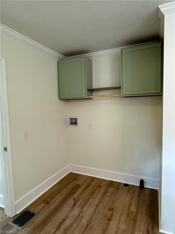 washroom featuring hookup for a washing machine, crown molding, dark wood-type flooring, and cabinets