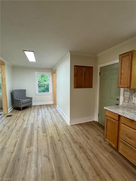 interior space featuring crown molding, light hardwood / wood-style floors, and tasteful backsplash