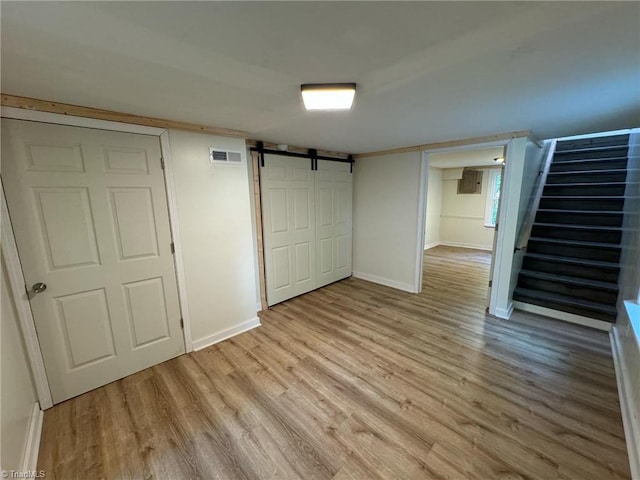 basement featuring light wood-type flooring and a barn door