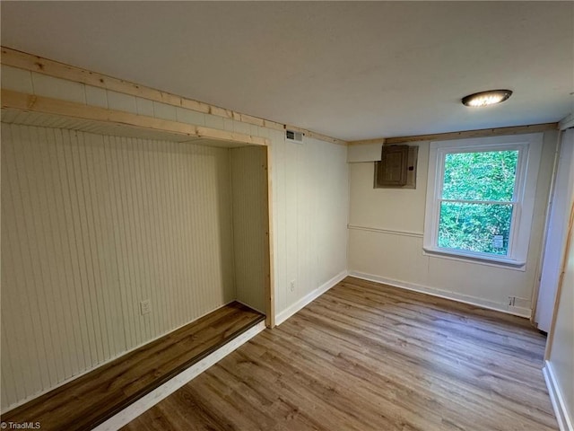 empty room with electric panel and light hardwood / wood-style floors