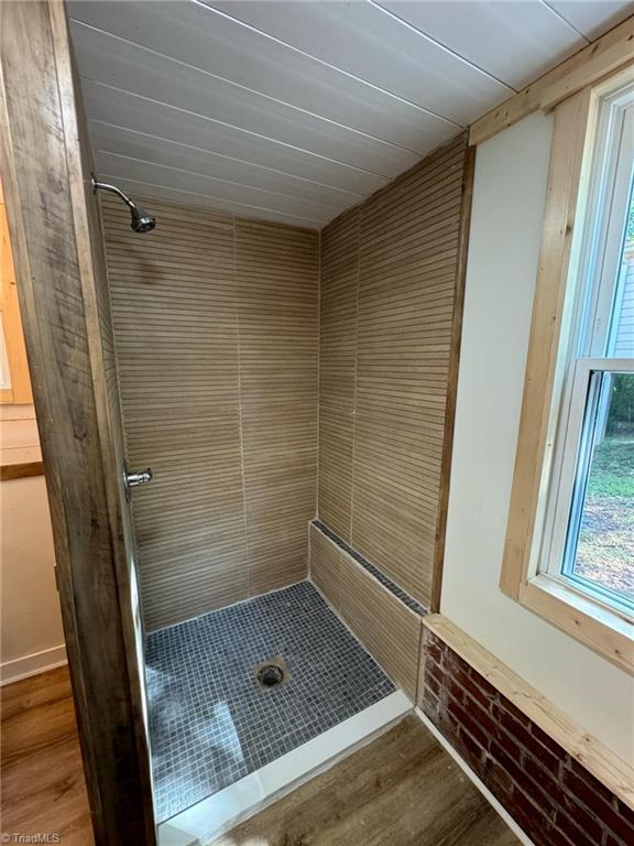 bathroom with a tile shower and hardwood / wood-style floors