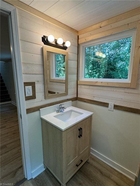 bathroom with wooden walls, vanity, hardwood / wood-style floors, and plenty of natural light