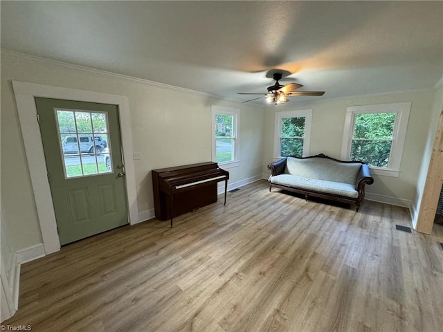 interior space with light wood-type flooring, ornamental molding, and ceiling fan