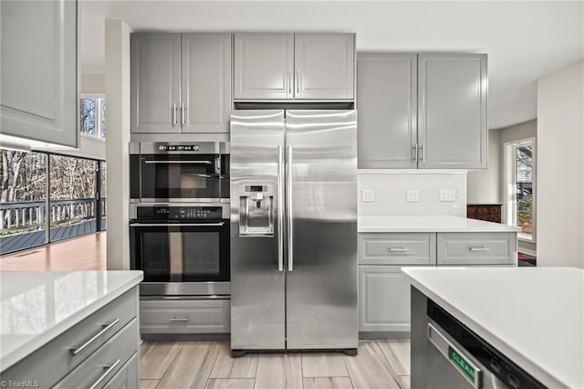 kitchen featuring stainless steel appliances, gray cabinetry, and light countertops