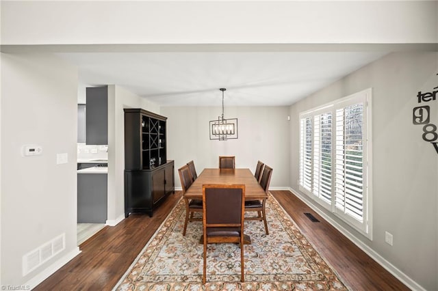 dining space featuring visible vents, baseboards, an inviting chandelier, and dark wood-style floors