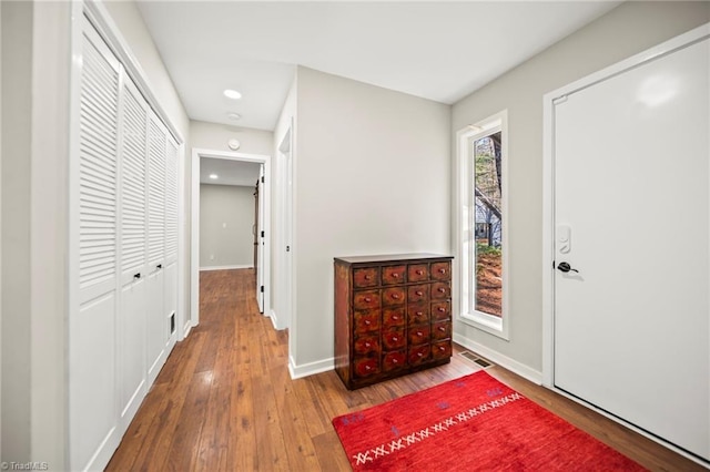 hall with hardwood / wood-style flooring, baseboards, and visible vents