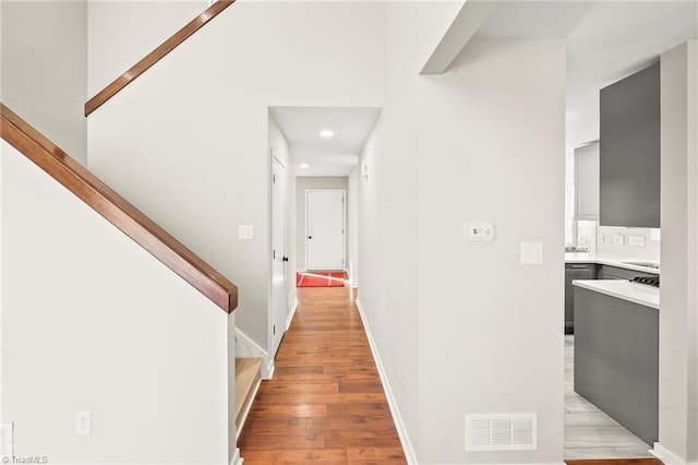 corridor featuring stairway, baseboards, visible vents, and light wood-type flooring