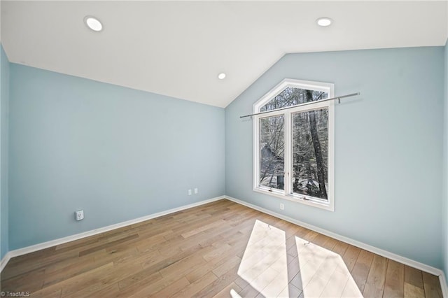 spare room with lofted ceiling, recessed lighting, wood finished floors, and baseboards