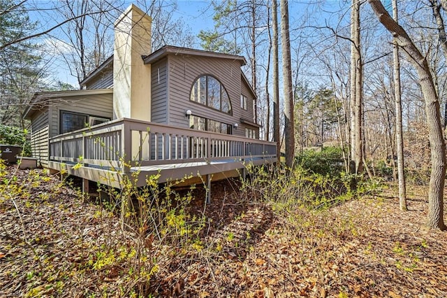 back of house with a chimney and a deck