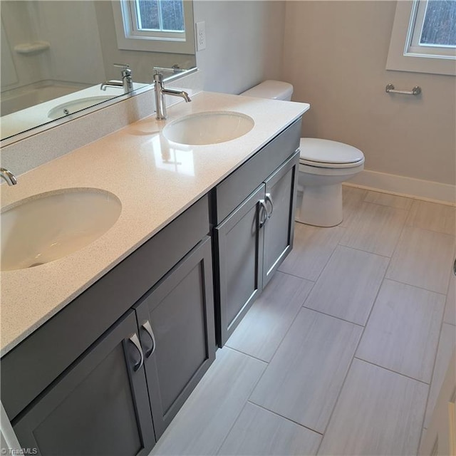 bathroom featuring toilet, vanity, and plenty of natural light