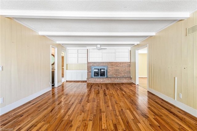 unfurnished living room with beamed ceiling, hardwood / wood-style floors, a textured ceiling, and a fireplace