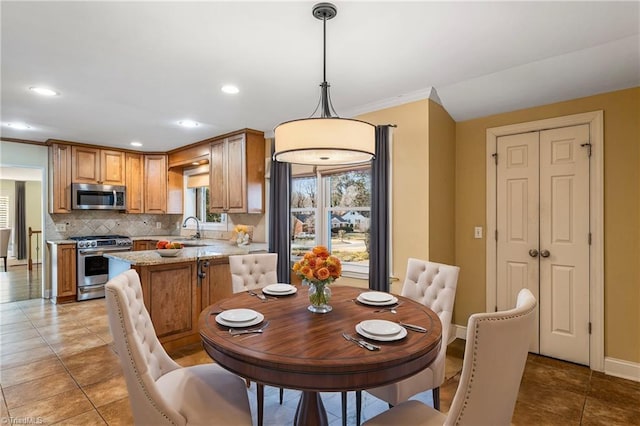 dining space featuring light tile patterned flooring, ornamental molding, and sink