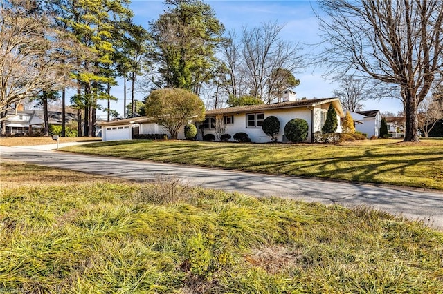 ranch-style home featuring a garage and a front lawn