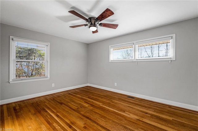 empty room with hardwood / wood-style flooring, plenty of natural light, and ceiling fan