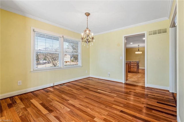 empty room featuring ornamental molding, hardwood / wood-style floors, and an inviting chandelier